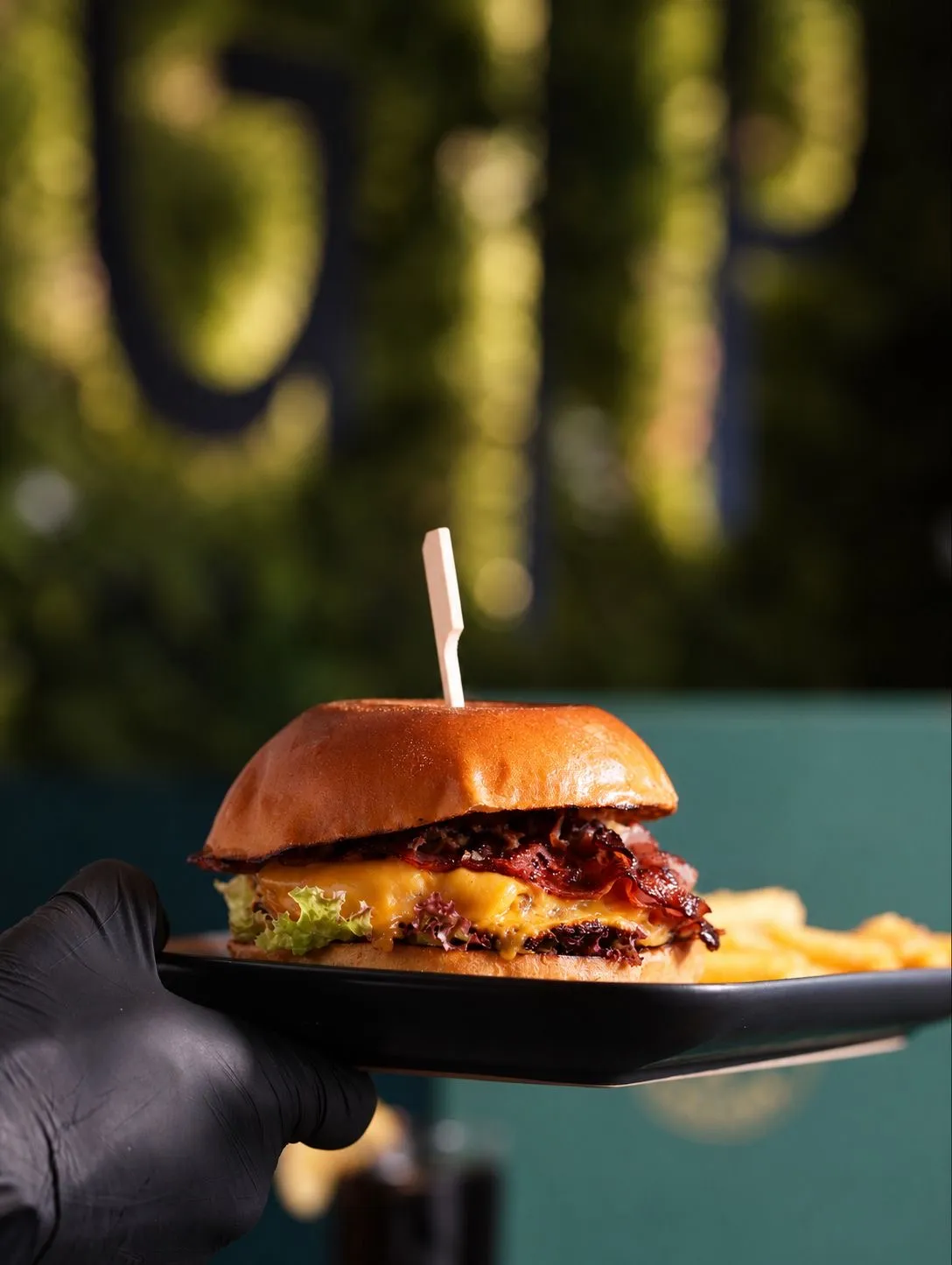 Burger mit Pommes vor der beleuchteten Wand