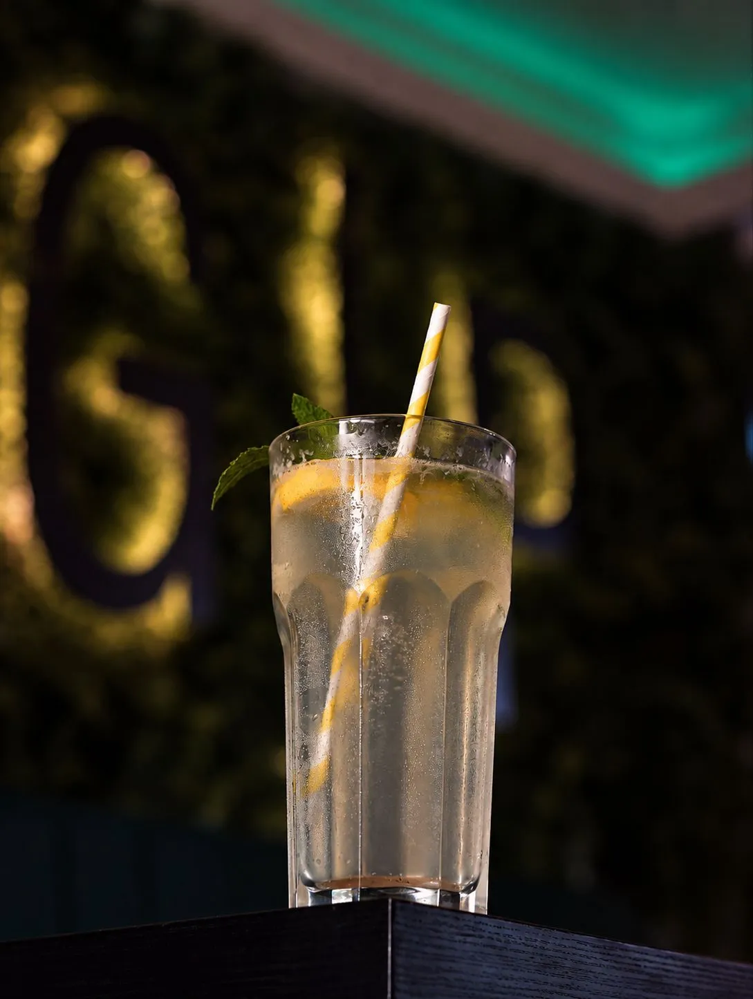 Helle Limonade mit Zitrone vor der Moos-Wand