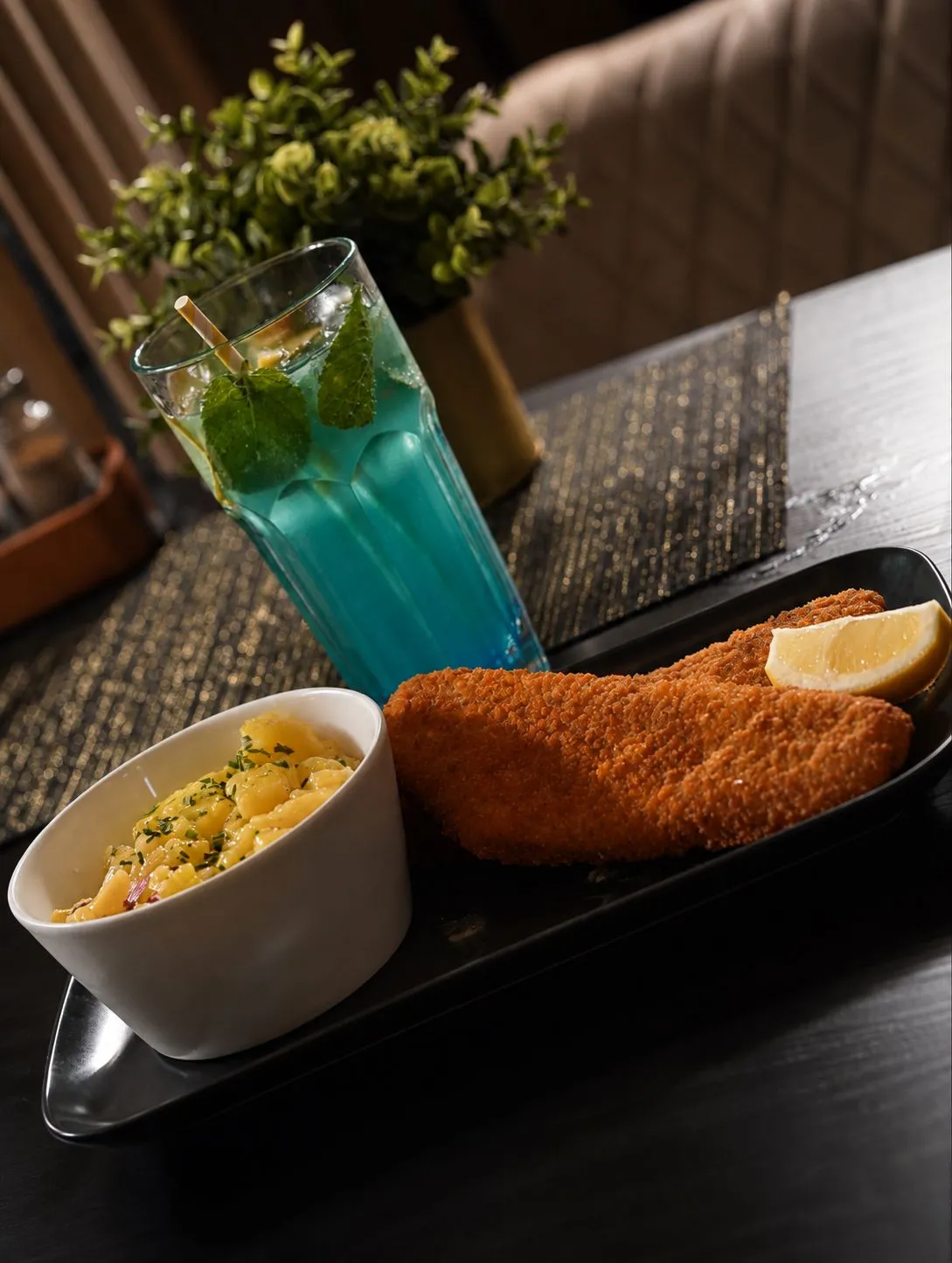 Schnitzelstreifen, Erdäpfelsalat und blaue Limonade auf dem Tisch